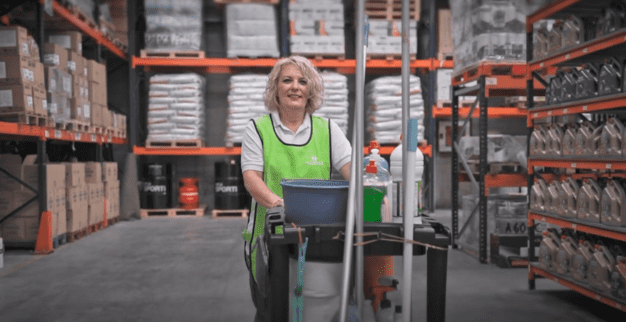 Trabajadora de limpieza en almacén con carrito