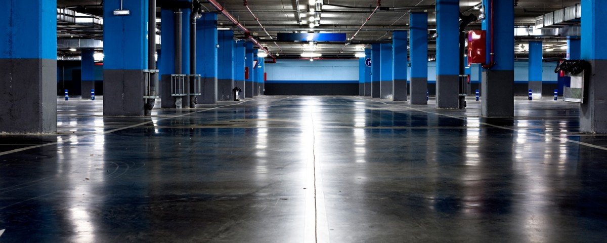 Aparcamiento subterráneo vacío con columnas azules.